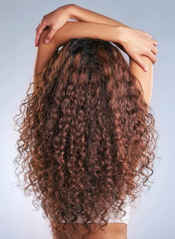 luminous-curly-haired-woman-arms-above-head